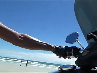 Motociclista de cuero sexy en botas de muslo en la playa